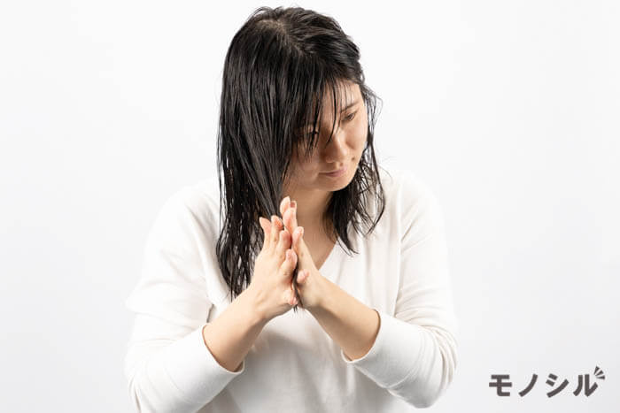 髪の中間から毛先にトリートメントをつける女性